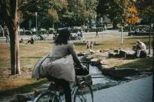 Frau in grauer Jacke auf einem Fahrrad durch den Stadtpark Bielefeld