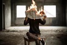  Person hält eine brennende Zeitung in verlassenem Gebäude