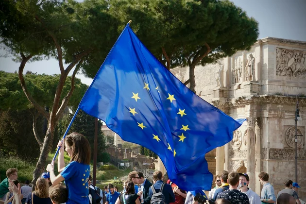 Eine junge Frau, die eine Europaflagge vor einer Menschenmenge hält.