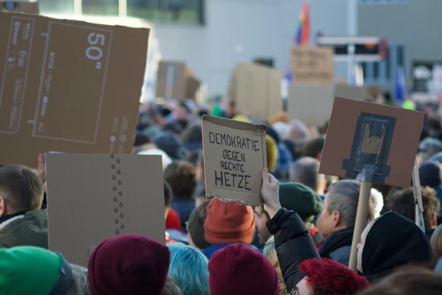 Eine Menschenmenge, die Schilder vor einem Gebäude hochhält. 